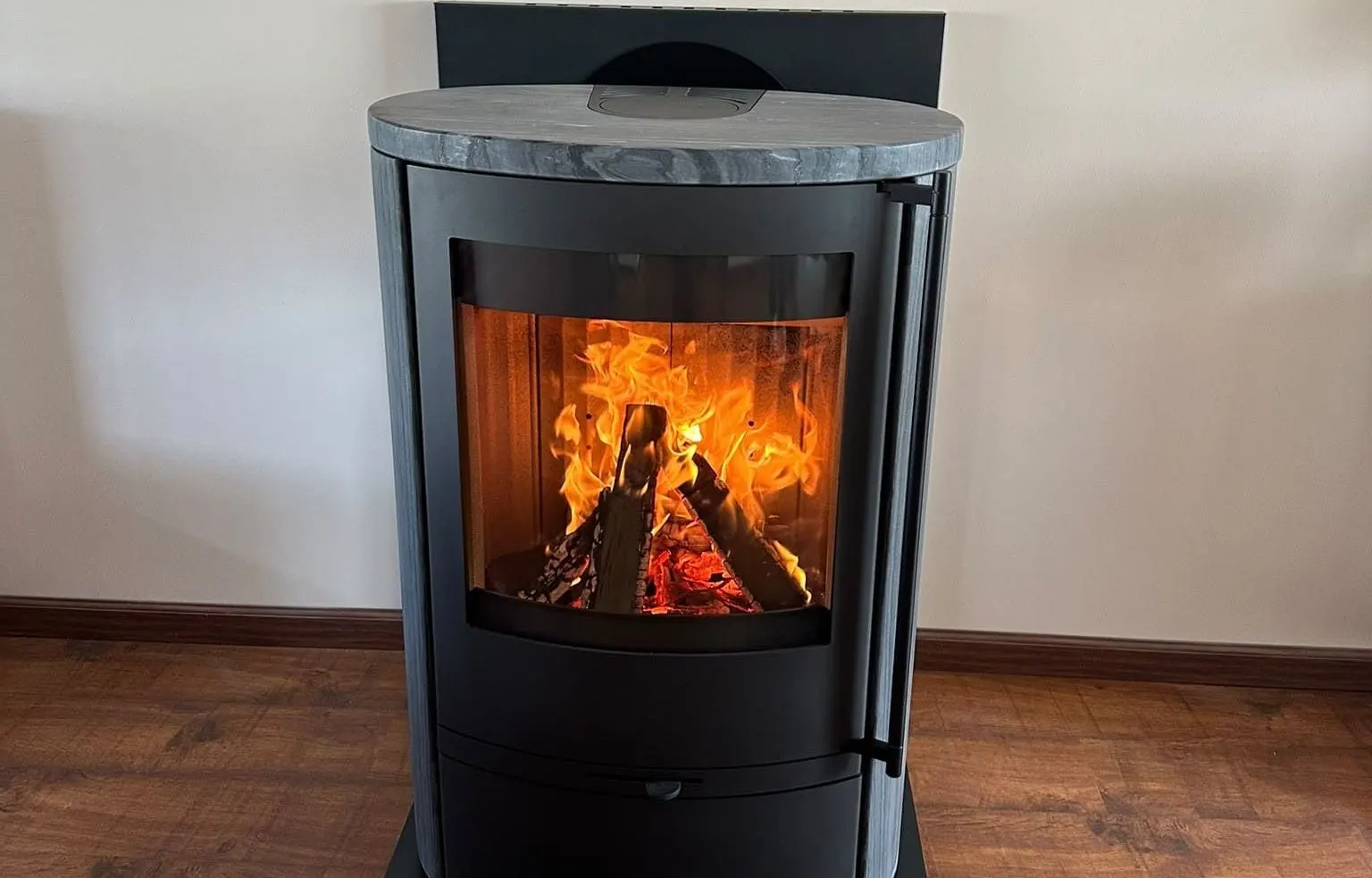 Poêle à bûches rond avec dessus en pierre et belle flambée, installé par Eco Chauffage Lorraine