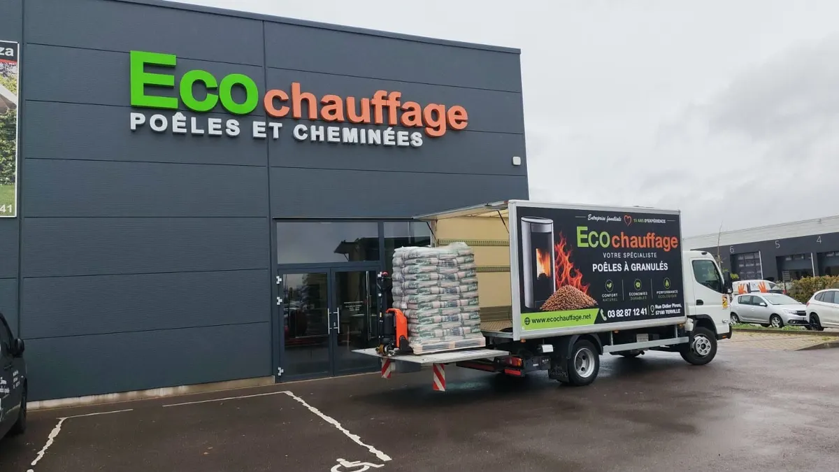 Camion Eco Chauffage déchargeant une palette de pellets avec hayon et transpalette devant le showroom de Terville